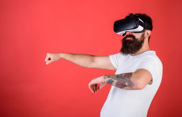 Man with beard in VR glasses driving car, red background. Virtual driving lessons concept. Hipster...