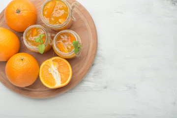 Orange jam in a glass jar on a light background. With an empty space for writing