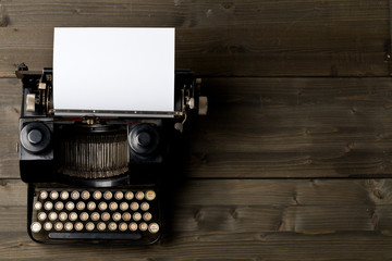 Vintage typewriter top down flatlay shot from above with empty, blank sheet of paper on wood table
