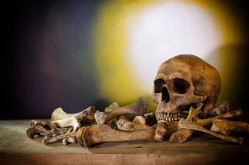 Skull and pile bones put on the wooden plank which has image moonlight on the wall background