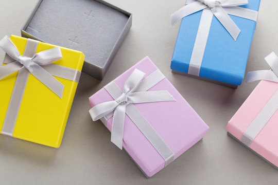 Small colorful jewelry gift boxes with bows on gray background