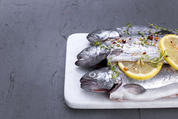 Raw fish. Trout with lemon and spices on a white stone board. Gray background. Free space for text. copy space. flat lay.