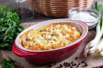 Baked casserole with a pumpkin on a wooden background