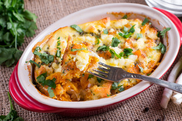 Baked casserole with a pumpkin on a wooden background