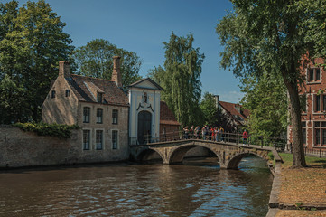 Fototapeta na wymiar Brick buildings and canal bridge with people in Bruges. With many canals and old buildings, this graceful town is a World Heritage Site of Unesco. Northwestern Belgium