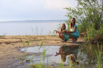 Dwie dziewczyny na brzegu jeziora, odbicie w wodzie.