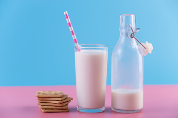 Bottle of fresh milk and a glass with a straw on a pastel background. Colorful minimalism. Healthy dairy products