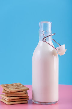 Glass bottle of fresh milk and cookies on pastel background. Concept of healthy dairy products with calcium