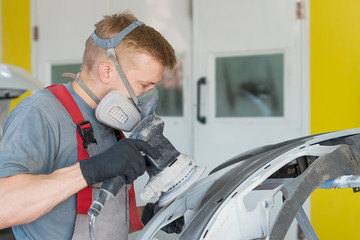 Fototapeta na wymiar An auto mechanic in a car repair service repairs a damaged car part