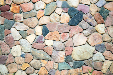 The wall is made of natural stone. Stone wall masonry is a natural material