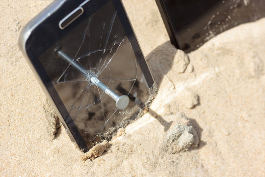 A nail in an old phone, it's punched. In the background a new phone