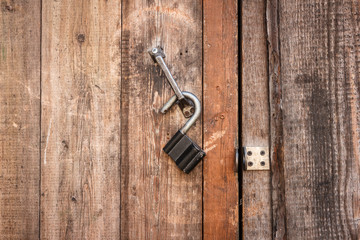 Vintage open padlock on an old shabby wooden door. Close-up view