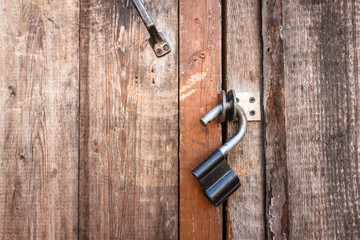 Vintage open padlock on an old shabby wooden door. Close-up view