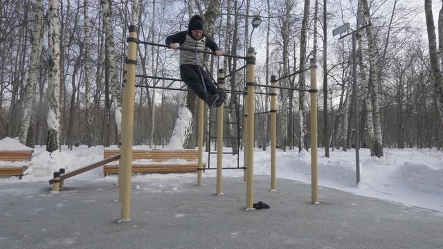 Young man training pull up exercise on crossbar during outdoor workout