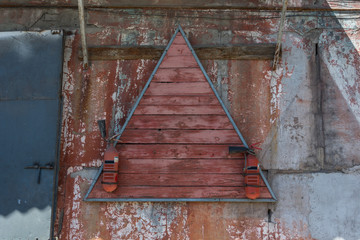Two red old fire extinguishers hang on a triangular wooden stand. Shabby wall of the production room.