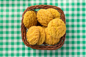 Delicious yellow cookie of corn on basket and green plaid table. Sweet food of Festa Junina, a typical brazilian party.