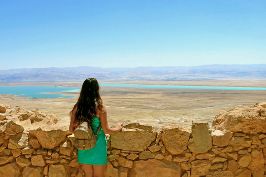 A young girl looks at the Dead Sea. Ruins of Herods Castle in  Masada Fortress in  Israel