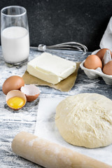 Dough mixing recipe bread, pizza or pie making ingridients, food flat lay on kitchen table background. Working with butter, milk, flour, eggs, sugar or bakery cooking.