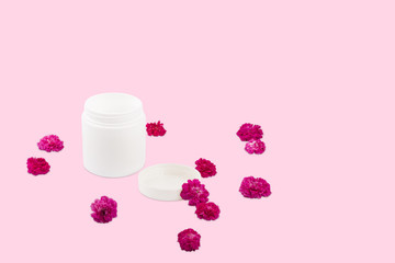 Obraz na płótnie Canvas White mocap jar for cream, balm, lotion and a small pink-Red roses on a pink background. Isolated, closeup. flatlay, copyspace
