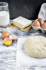 Dough mixing recipe bread, pizza or pie making ingridients, food flat lay on kitchen table background. Working with butter, milk, flour, eggs, sugar or bakery cooking.