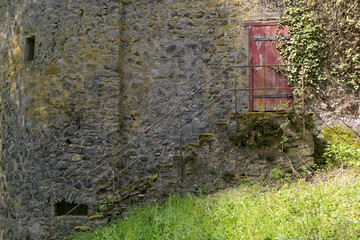 An old stone staircase with a broken, wooden door in the background.