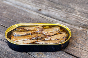 Open tin can of sprats on rustic wooden table