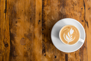 Cup of coffee to go on the wooden table with latte art. Street coffee. Top View
