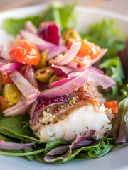 Close-up of cod fillet sallad. Fresh food with bacon.