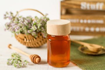 Thyme honey in a  jar with fresh flowers on a white wooden background