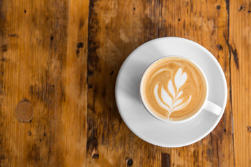 Cup of coffee to go on the wooden table with latte art. Street coffee. Top View