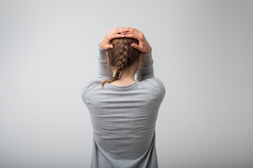 standing young woman, back view. She is holding her head in depression. Concept of negative despair...