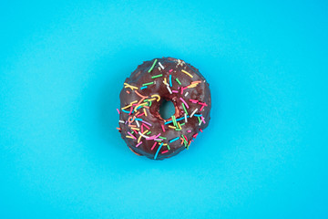 Donuts on blue background. Pile of fresh homemade donuts with icing and colorful sprinkles. 