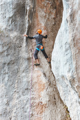 A man in helmet climbs the rock.