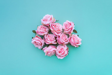 Several satin pink rose buds on green pastel background. Top view.