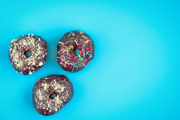 Donuts on blue background. Pile of fresh homemade donuts with icing and colorful sprinkles. 