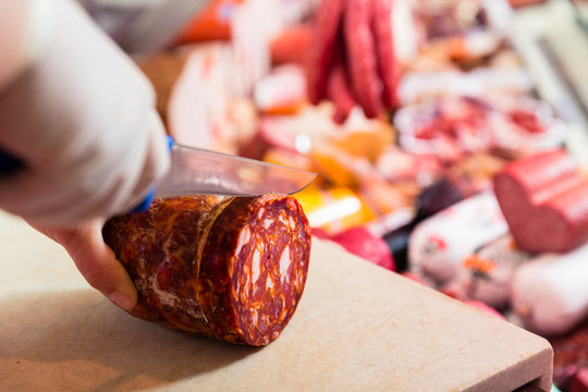 Frau in Fleischerei schneidet Chorizo Wurst