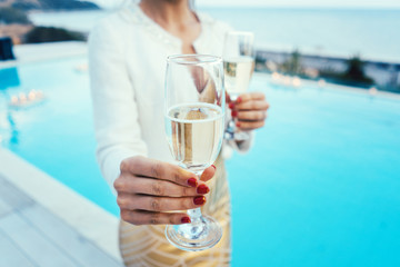 Frau gibt Mann Glas Sekt auf Pool und Strand party