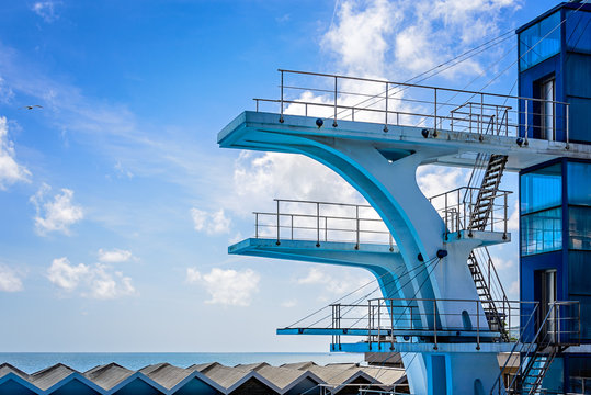 High tower for diving at public swimming pool and summer sky with gull as background. Vintage Vision. Concept of challenge and adrenaline.