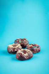 Donuts on blue background. Pile of fresh homemade donuts with icing and colorful sprinkles. 