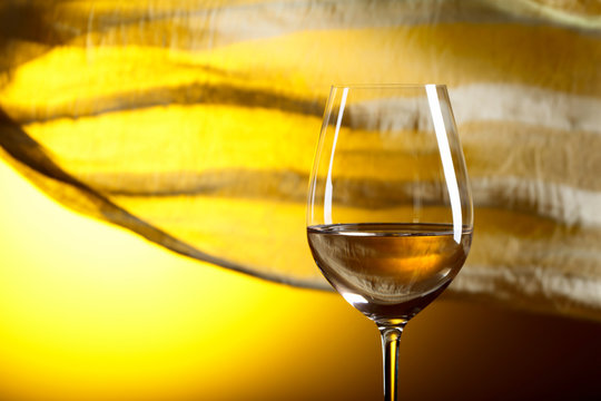 Glass of white wine on a yellow background.