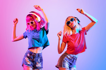 DJ Girl with Pink Blond Fashion Hairstyle Dance. Two Young Playful Hipster in Trendy Headphones....