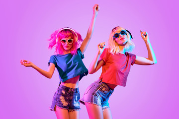 DJ Girl with Pink Blond Fashion Hairstyle Dance. Two Young Playful Hipster in Trendy Headphones....