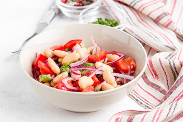 Salad with white beans, tomatoes, red onions, green coriander, parsley, delicious diet lunch