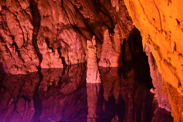 Stalagmites emerging from the lake in the cave. Calcareous deposits. Stalactites
