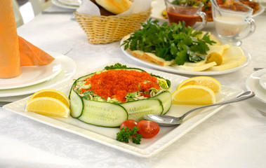 Seafood salad with vegetables and red caviar on the table.