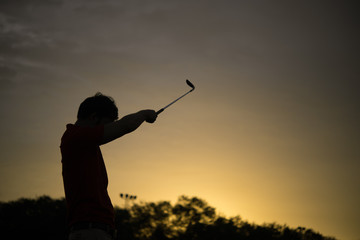Fototapeta na wymiar silhouette asian golfer playing golf during beautiful sunset,Thailand people