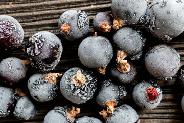 frozen black currant berries on wooden background, top view, macro
