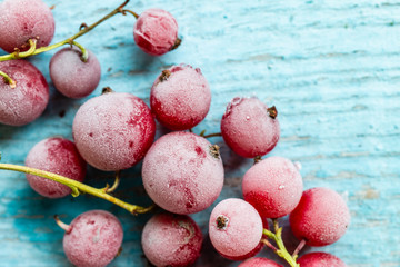 frozen berries of red currant on blue colored wooden background, top view. macro.