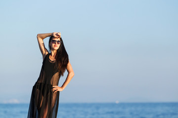 Fototapeta na wymiar attractive young woman with long dark hair in black swimwear and transparent dress. concept of happy holiday and resort time