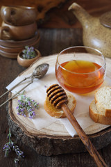 Lavender honey in glass jar, flowering lavender and slices of baguette